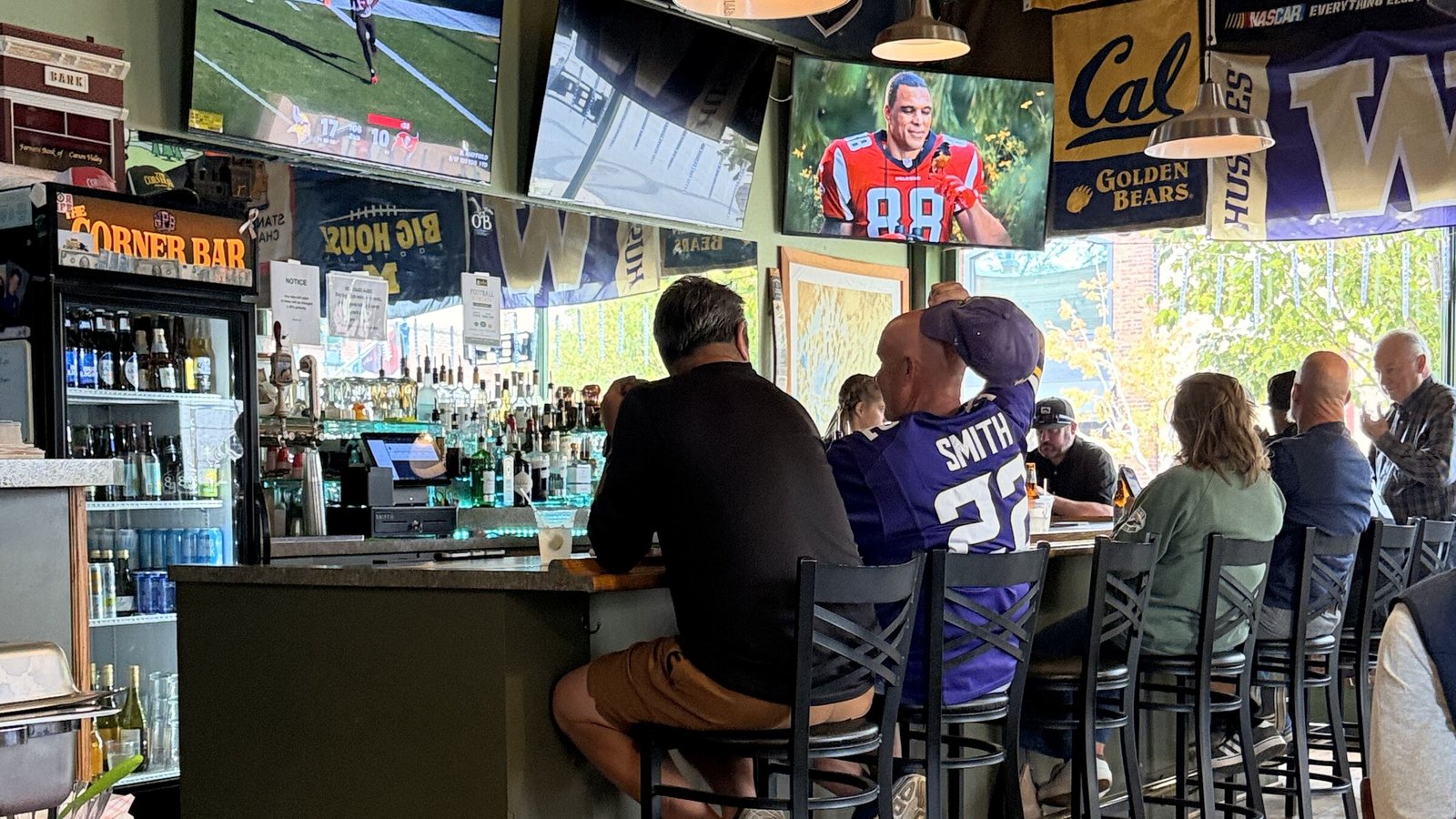 Regulars at the bar under the TVs and the Corner Bar sign